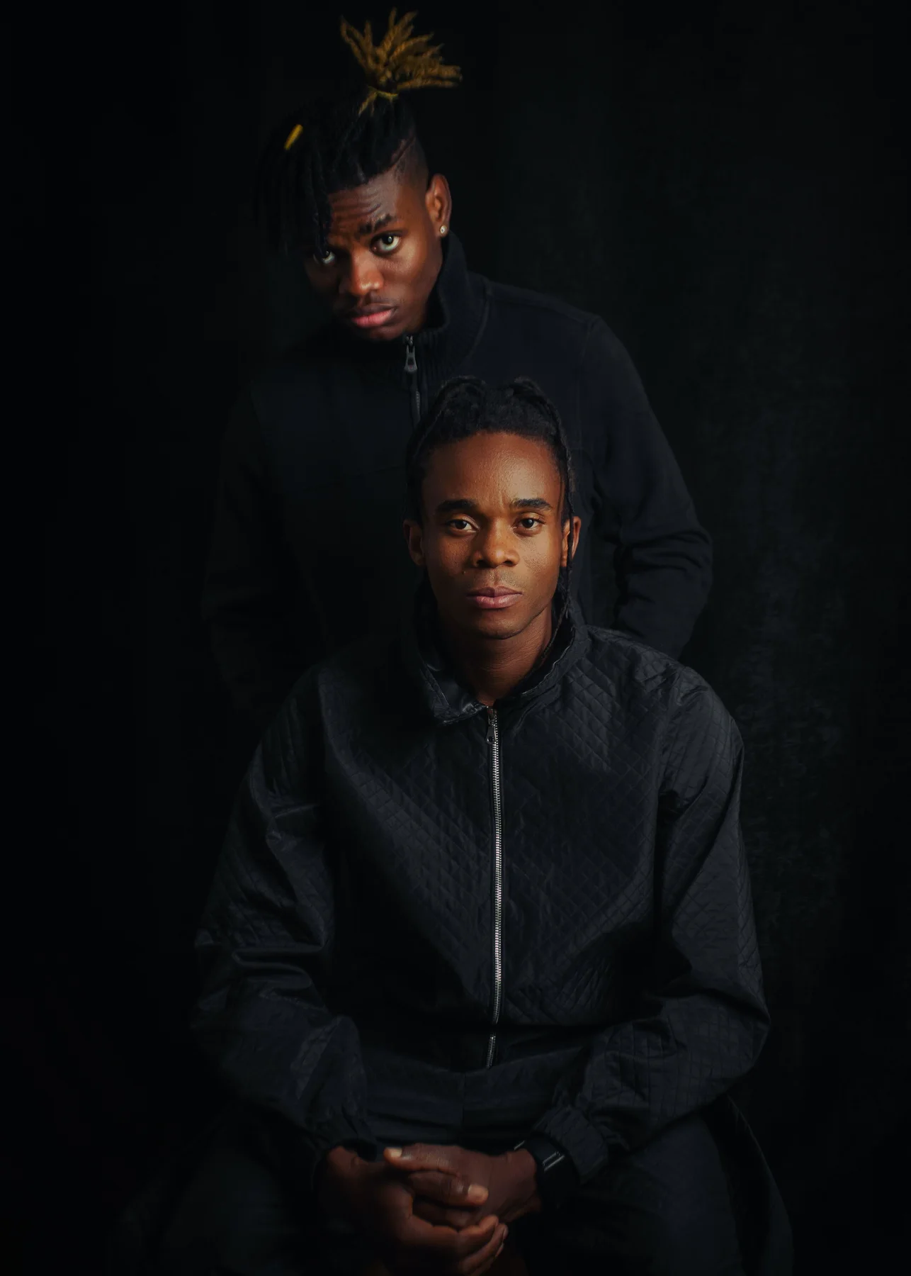 Deux hommes posant dans un portrait de mode aux tons sombres
