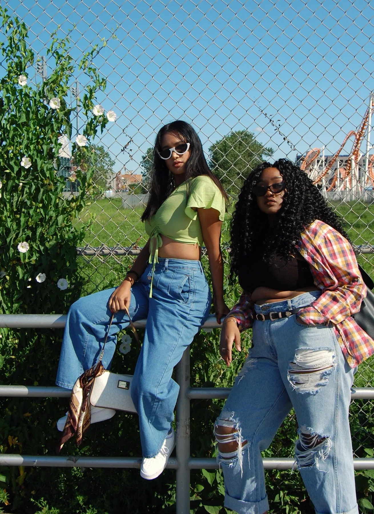 Deux femmes en looks décontractés devant une grille ensoleillée