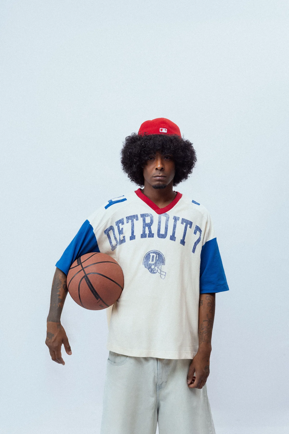 Homme tenant un ballon de basket dans une tenue inspirée du sport vintage